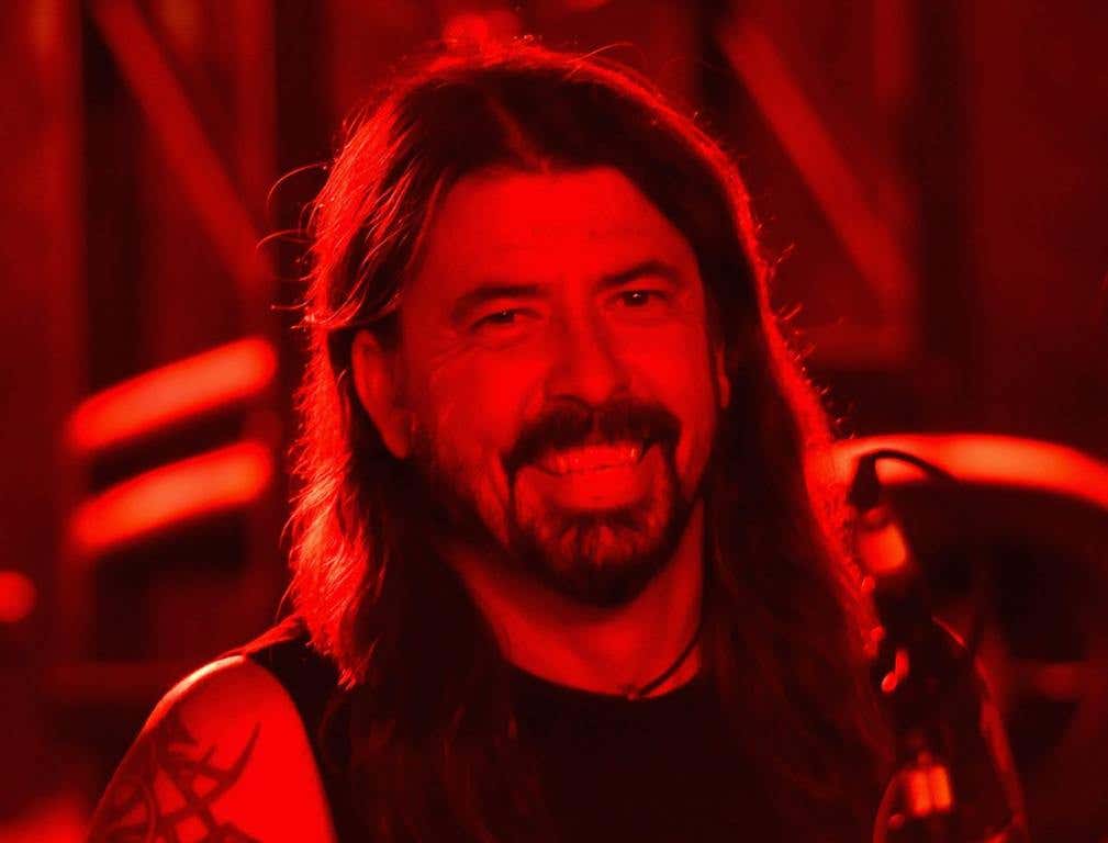 Dave Grohl smiling while sitting behind the drums.