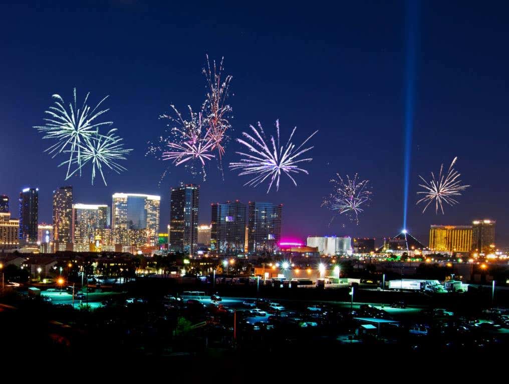 This image shows a distant view of the Las Vegas Strip at night time as a variety of fireworks explode above the casinos and hotels.