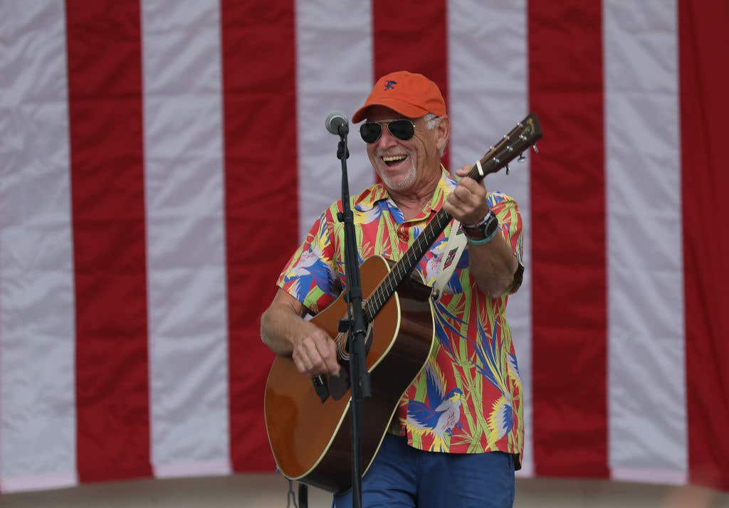 Jimmy Buffett Performs At Get Out The Vote Rally . He's performing in front of an American flag.