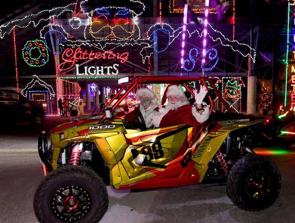 : Mrs. Claus and Santa Claus characters pose in a side-by-side utility vehicle during the opening night of the Glittering Lights drive-thru light show at the Las Vegas Motor Speedway on November 13, 2020 in Las Vegas, Nevada. The annual holiday display features 5 million lights along a 2.5-mile course.