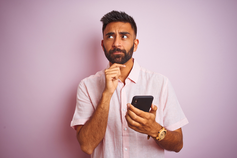 Man with phone in hand wondering if he should answer the call