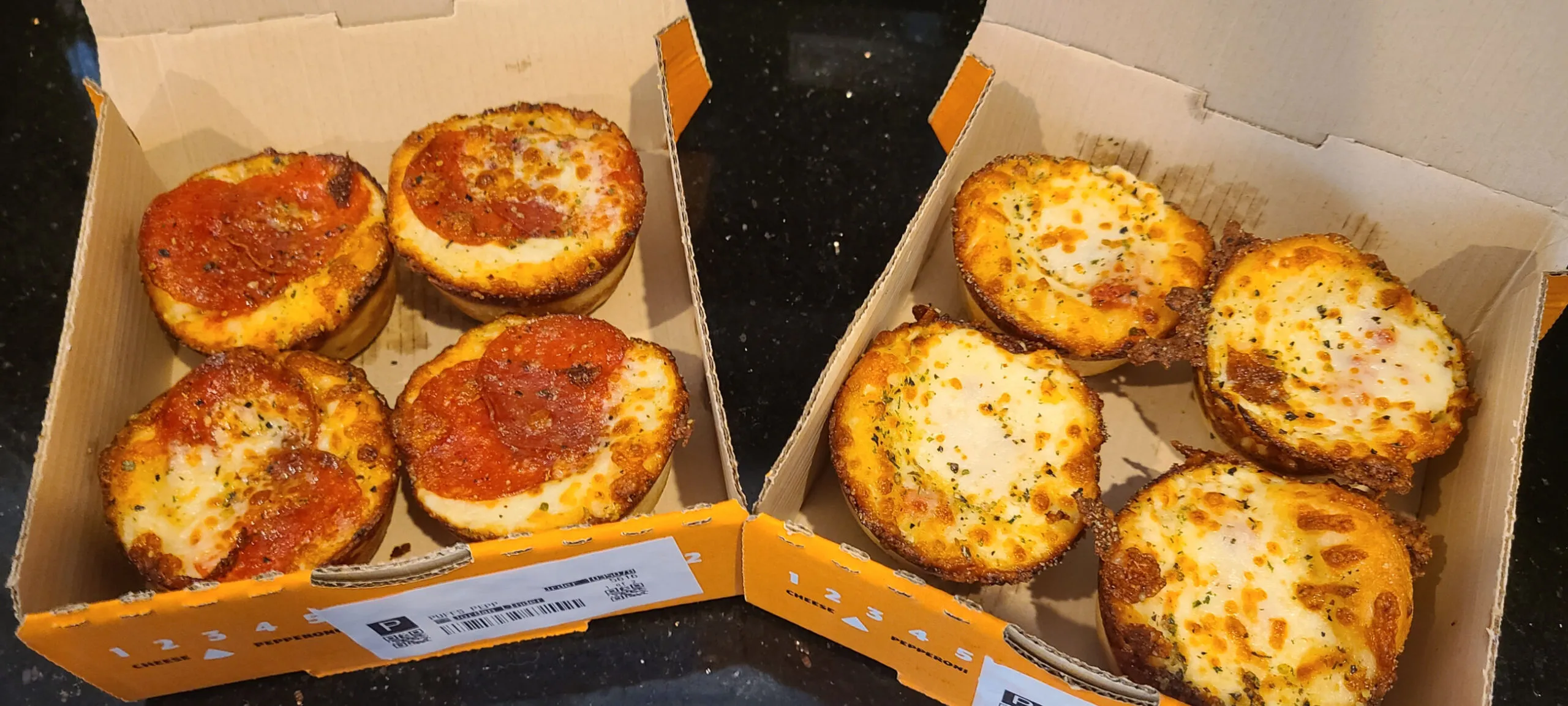 This image shows an open box of Little Caesars' Pepperoni Crazy Puffs and an open box of their Cheese Puffs. Inside the box are four puffs of their respective types.