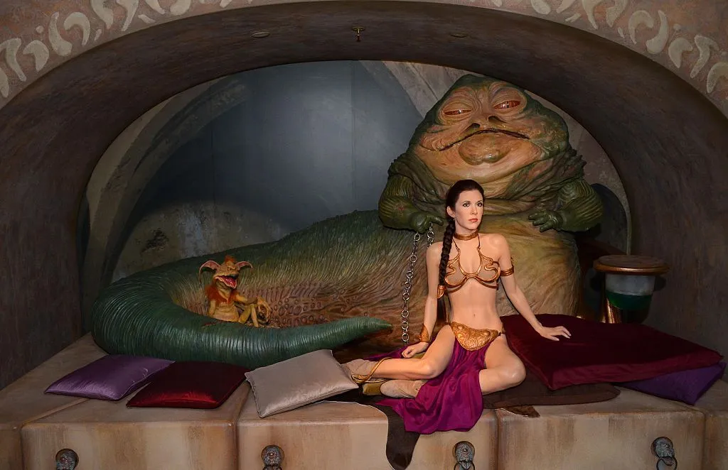 A wax figure of Carrie Fisher in the famous gold bikini sits in front of a wax figure of Jabba the Hut.